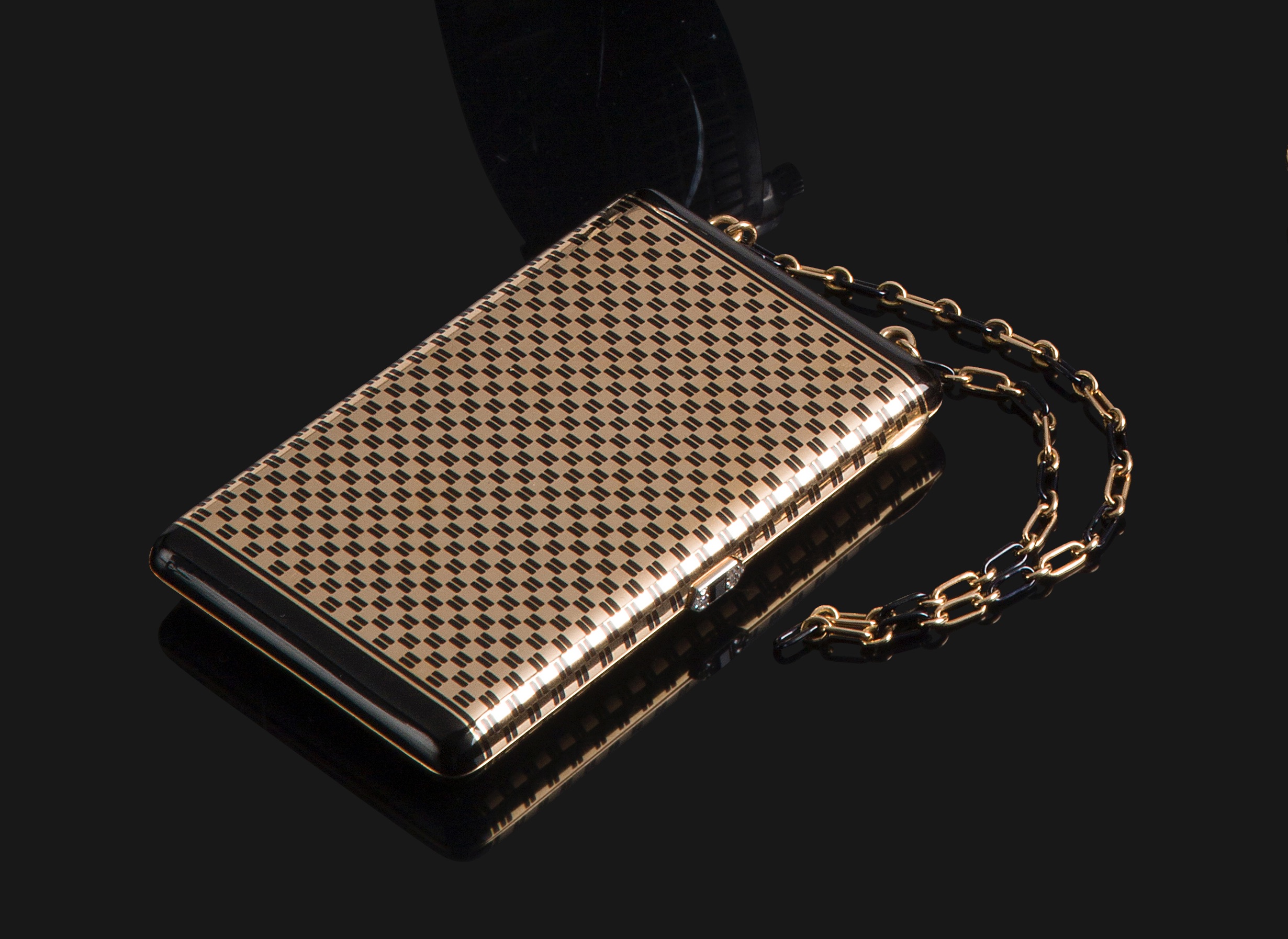 CARTIER Nécessaire du soir en or 18K à décor laqué de motifs géométriques, le poussoir serti d'un onyx épaulé de diamants taillés en roses ; retenu par une chaînette formé d'anneaux en or et d'anneaux laqué alternés.